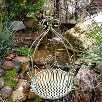 Iron hanging planter basket in natural rockery garden setting - vintage distressed metal flower holder